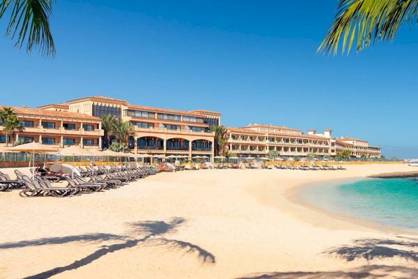 Strand des Secrets Bahia Real Resort & Spa mit vielen Liegestühlen und einem großen Hotelgebäude