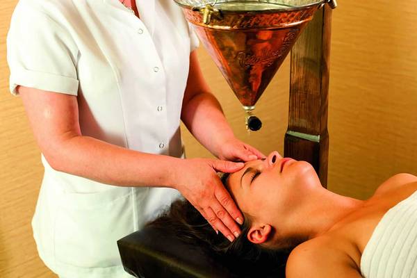 Eine Kosmetikerin im Royal Alhambra Palace führt eine Gesichtsmassage an einer Frau durch.