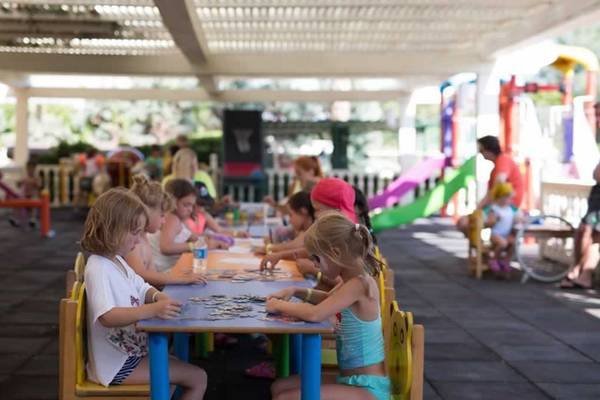 Kinder sitzen an einem Tisch im Freien und arbeiten an einem Puzzle im Royal Alhambra Palace.