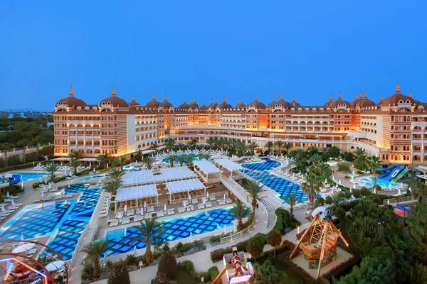 Außenansicht des Royal Alhambra Palace Hotels bei Nacht mit beleuchteten Gebäuden und Pools.