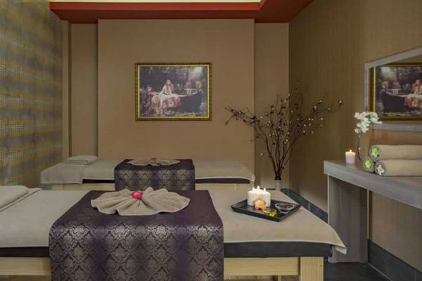 Spa-Behandlungsraum im Royal Alhambra Palace mit zwei Massagebetten, Kerzen und Kunstwerken an den Wänden.