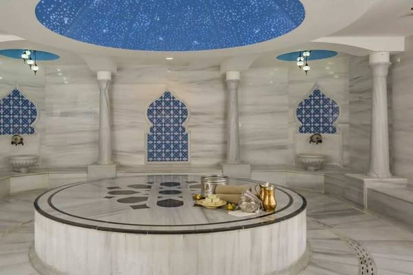 Innenansicht der Sauna im Royal Alhambra Palace mit weißem Marmorboden und blauen Wandverzierungen.