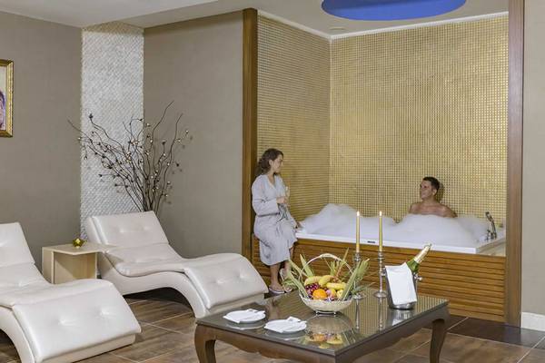 Behandlungsraum im Royal Alhambra Palace Spa mit zwei Liegestühlen, einer Badewanne und Obstkorb.