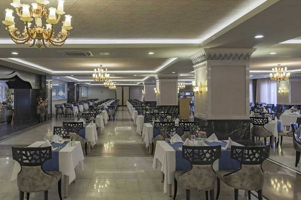 Ein elegant eingerichtetes Restaurant im Royal Alhambra Palace mit gedeckten Tischen und Kronleuchtern.