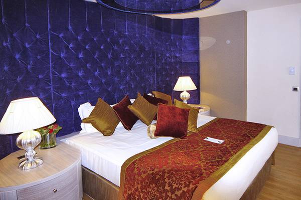 Schlafzimmer im Royal Alhambra Palace Hotel mit blauem Wandbezug und weißen Laken.