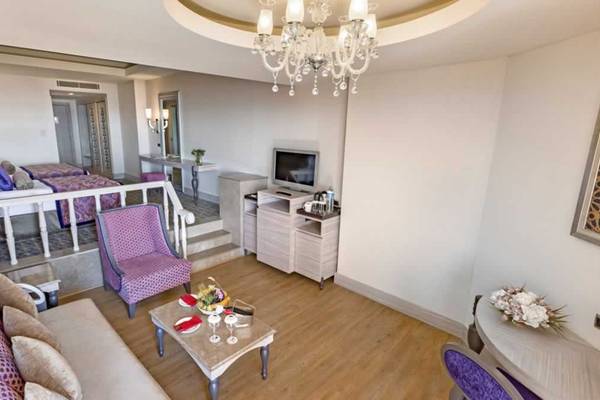 Innenansicht einer Suite im Royal Alhambra Palace Hotel mit Wohnzimmer, Schlafzimmer und Fernseher.