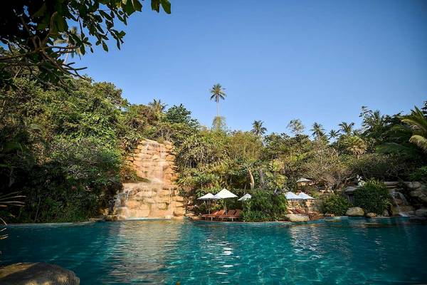 Außenpool mit Sonnenliegen und Wasserfall im Santhiya Koh Phangan Resort & Spa.