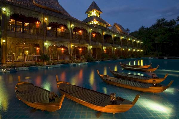 Shanthiya Koh Phangan Resort & Spa bei Nacht mit beleuchteten Gebäuden und Booten im Pool