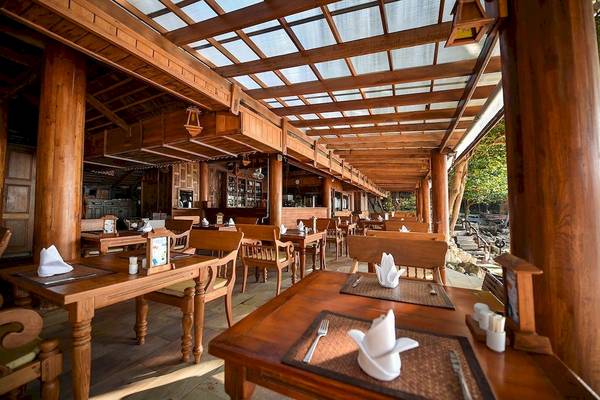Innenansicht des Restaurants im Santhiya Koh Phangan Resort & Spa mit hölzernen Tischen und Stühlen.
