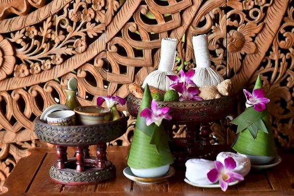 Massage-Utensilien im Santhiya Koh Phangan Resort & Spa, einschließlich Kräutersäckchen, Blumen und Öl.