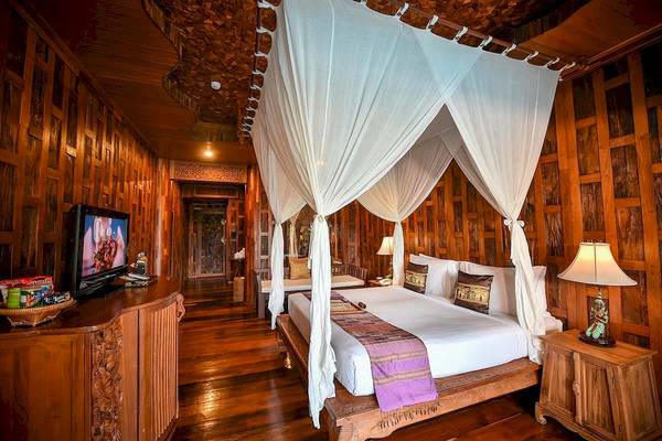 Zimmer im Santhiya Koh Phangan Resort & Spa mit einem Bett unter einem Baldachin.