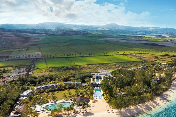Luftaufnahme des Outrigger Mauritius Beach Resorts mit Blick auf die Küste, Gebäude, Swimmingpool und grüne Landschaft.