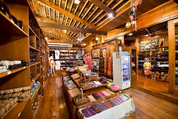 Innenansicht eines Ladens im Santhiya Koh Phangan Resort mit Holzboden, Regalen und verschiedenen Produkten.