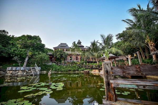 Santhiya Koh Phangan Resort & Spa mit einem großen Teich und einem hölzernen Steg.