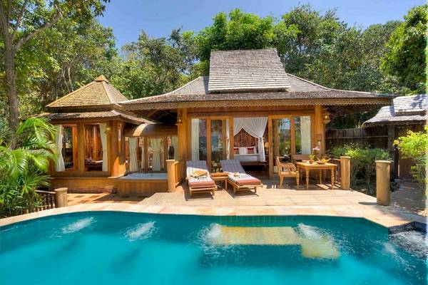 Außenbereich des Santhiya Koh Phangan Resort & Spa mit Pool, Lounge-Liegestühlen und einem kleinen Tisch.