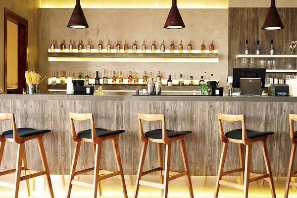 Innenansicht der Bar im Ostria Resort & Spa mit hölzernen Barhockern und Theke.