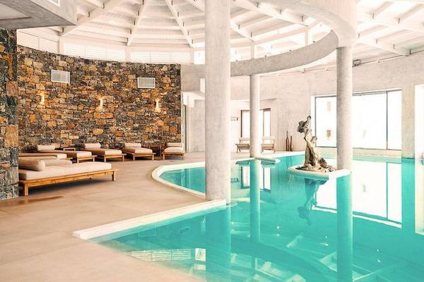 Innenpool des Ostria Resort & Spa mit Lounge-Bereich und Steinwand