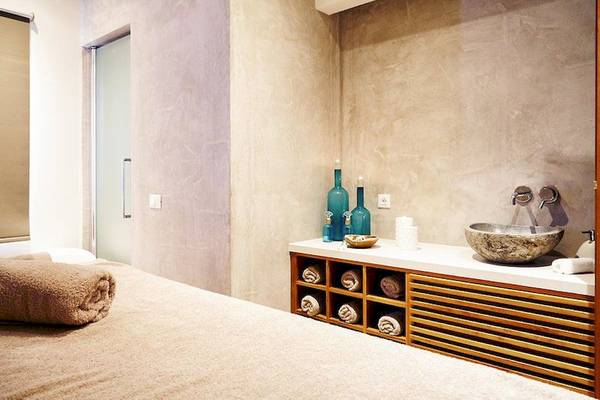 Massageraum im Ostria Resort & Spa mit beigefarbener Einrichtung und blauen Flaschen.