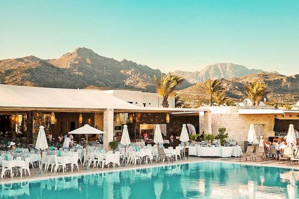 Außenbereich des Ostria Resort & Spa mit Swimmingpool und Tischen vor einem Gebäude.