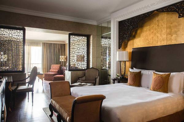 Ein elegantes Hotelzimmer im Jumeirah Zabeel Saray mit einem großen Bett, dekorativen Lampen und einem eleganten Kopfteil.