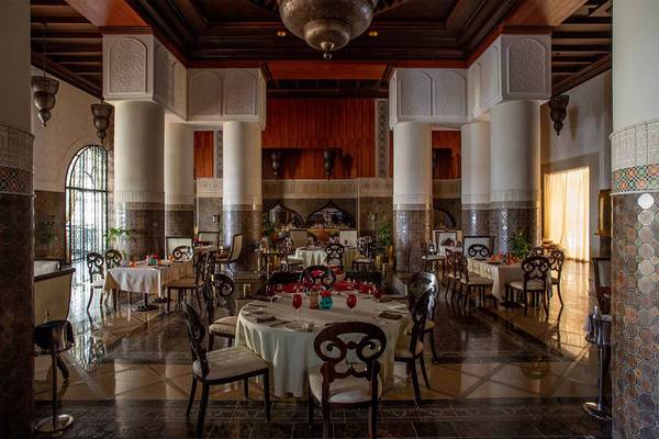 Innenraum des Jumeirah Zabeel Saray Hotels mit vielen gedeckten Tischen und Stühlen.
