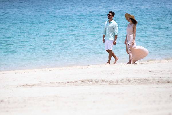 Paar spaziert am Strand vor dem Jumeirah Zabeel Saray Hotel