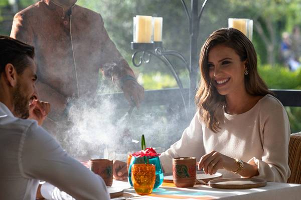Ein Paar genießt ein Essen im Freien im Jumeirah Zabeel Saray, während ein Kellner im Hintergrund steht.