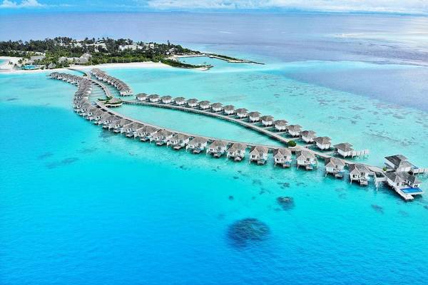 Luftaufnahme des Kandima Maldives Resorts mit Wasservillen im Meer.