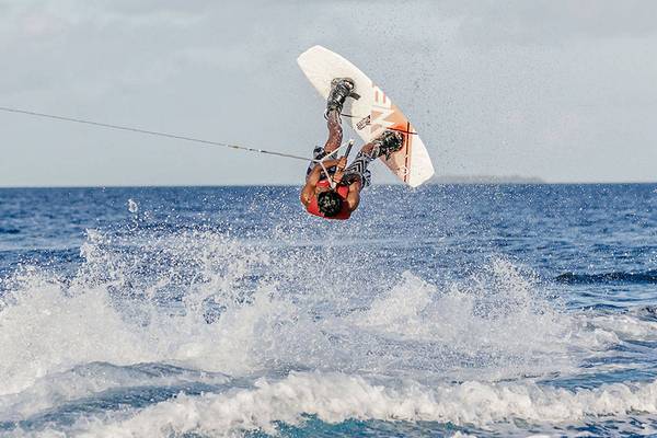 Person im Ozean beim Surfen auf einem Segelboot, das umgedreht ist.