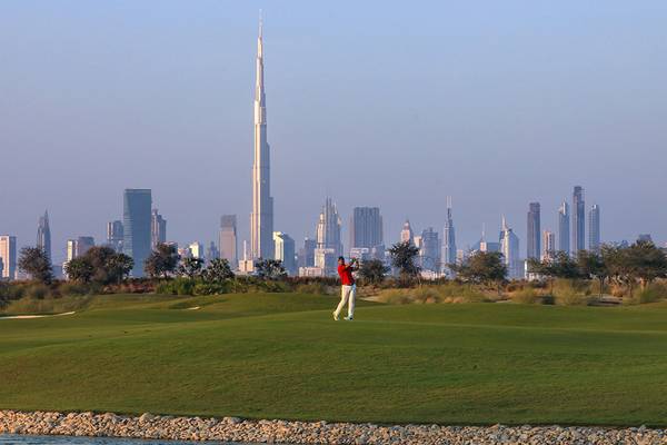 Golfplatz mit einem Spieler im Vordergrund und der Skyline von Dubai im Hintergrund.