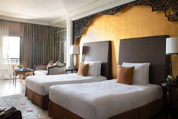 Doppelbettzimmer im Jumeirah Zabeel Saray Hotel mit zwei Betten, goldenen Wänden und orientalischen Lampen.