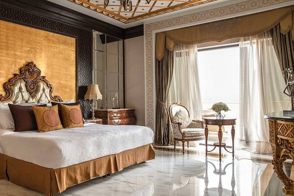Luxuriöses Hotelzimmer im Jumeirah Zabeel Saray mit goldener Wand, Bett, Stühlen und Tisch.
