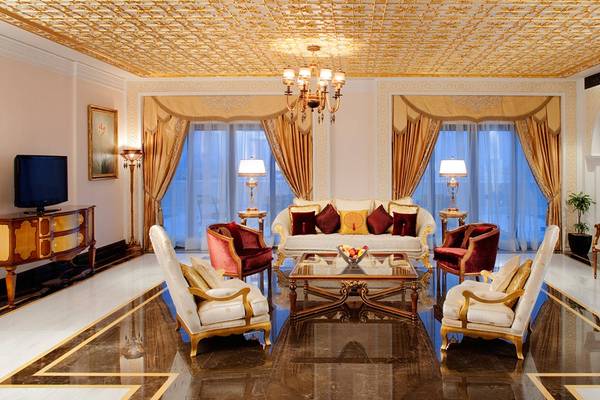 Wohnzimmer im Jumeirah Zabeel Saray Hotel mit einem Sofa, Lampen und einem Fernseher.