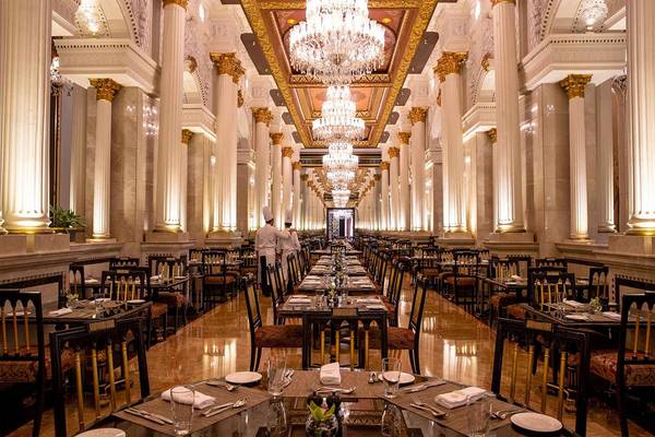 Innenansicht des Restaurants im Jumeirah Zabeel Saray Hotel mit langen Tischen, Stühlen und Kristallkronleuchtern.
