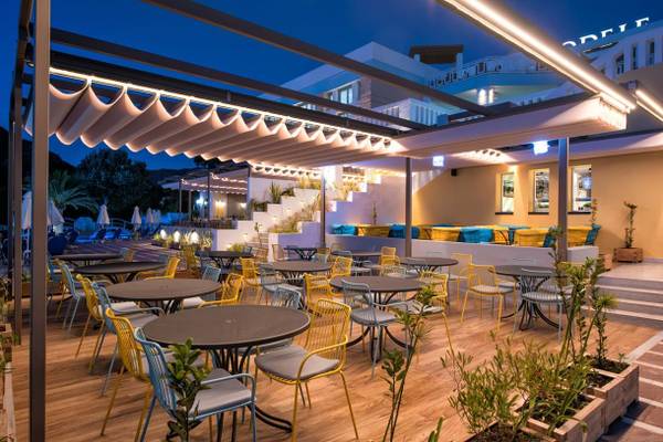 Außenbereich des Fodele Beach & Water Park Holiday Resort bei Nacht mit beleuchteten Tischen und Stühlen.