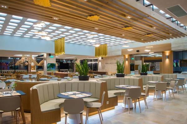Innenansicht des Restaurants im Fodele Beach & Water Park Holiday Resort mit Holzmöbeln und Pflanzen.