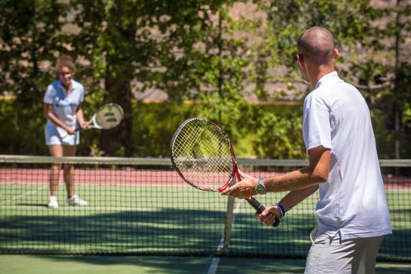 Tennisspieler auf Tennisplatz im Freien mit Frau im Hintergrund