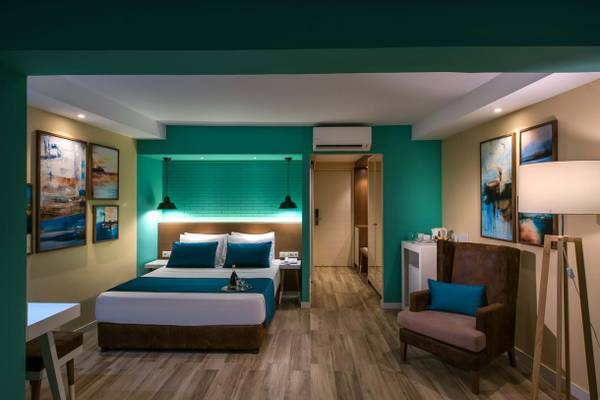 Doppelzimmer im Fodele Beach & Water Park Holiday Resort mit türkisfarbenen Wänden und Holzboden.