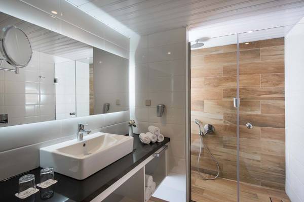 Badezimmer im Fodele Beach & Water Park Holiday Resort mit ebenerdiger Dusche, Waschbecken und Spiegel.