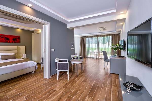 Innenansicht eines Hotelzimmers im Fodele Beach & Water Park Holiday Resort mit Bett, Tisch und Fernseher.