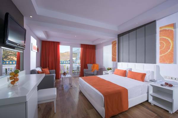 Innenansicht eines Hotelzimmers im Fodele Beach & Water Park Holiday Resort mit Bett, Möbeln und Balkon.