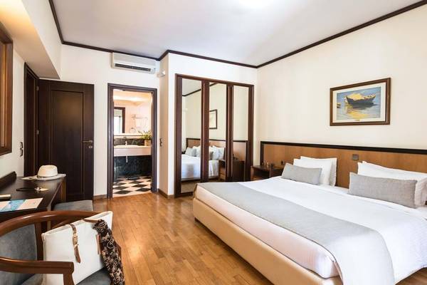 Innenansicht eines Hotelzimmers im Fodele Beach & Water Park Holiday Resort mit Doppelbett, Schreibtisch, Spiegeln und Fernseher.