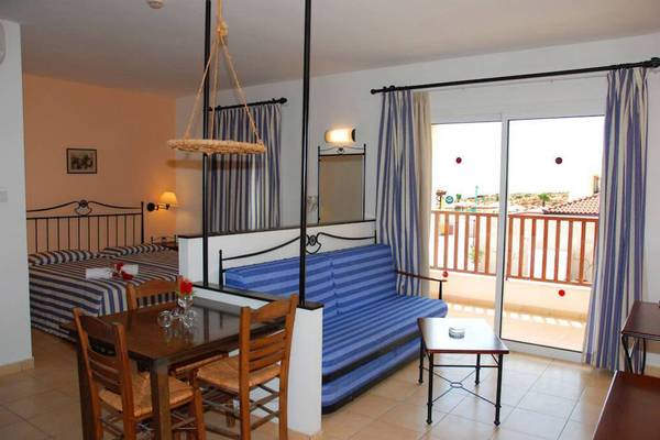 Aktea Beach Village Zimmer mit Balkon, Tisch, Sofa und Schlafzimmer.