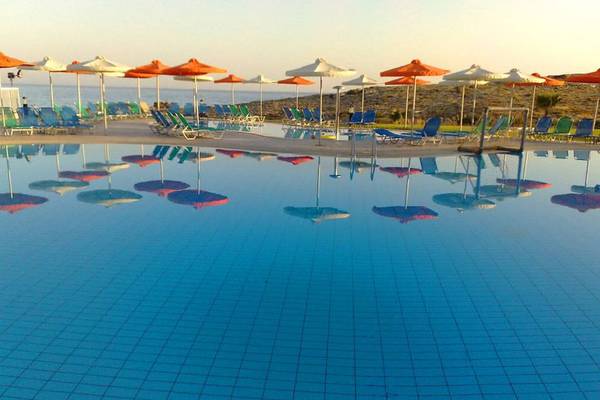 Pool im Aktea Beach Village Hotel mit vielen Sonnenliegen und Sonnenschirmen am Rand.