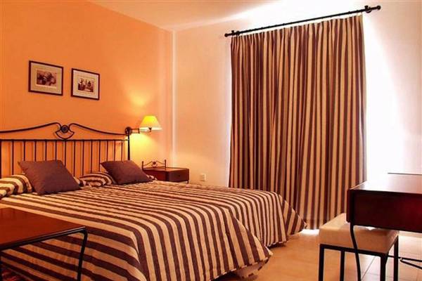 Doppelzimmer im Aktea Beach Village Hotel mit zwei Betten, Tisch, Stuhl, Lampe und Wanddekoration.