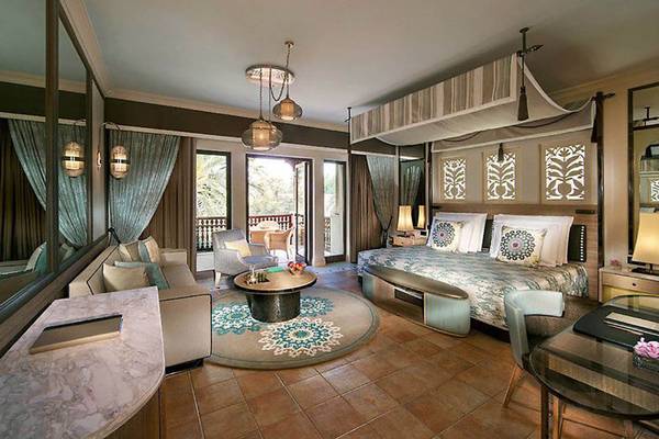 Innenansicht der Suite im Jumeirah Dar Al Masyaf Hotel mit großem Bett, Wohnzimmerbereich und Terrasse.