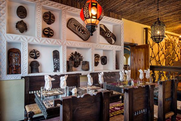 Innenbereich des Bahari Zanzibar Restaurants mit afrikanischen Masken und Lampen an der Wand.