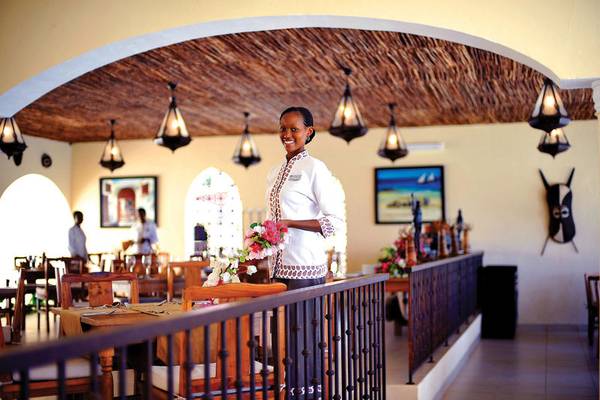 Mitarbeiterin des Bahari Zanzibar Hotels mit Blumen im Innenbereich des Restaurants