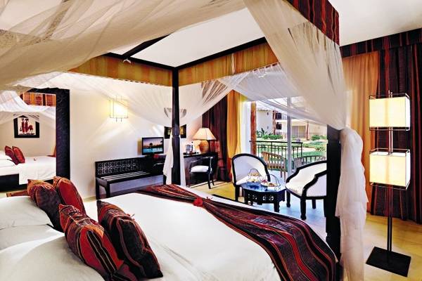 Schlafzimmer im Bahari Zanzibar Hotel mit einem vierposterbett, weichen kissen und einem balkon.