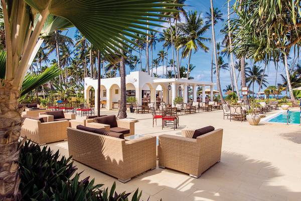 Außenbereich des Bahari Zanzibar Hotels mit Lounge-Sesseln, Tischen und Palmen.